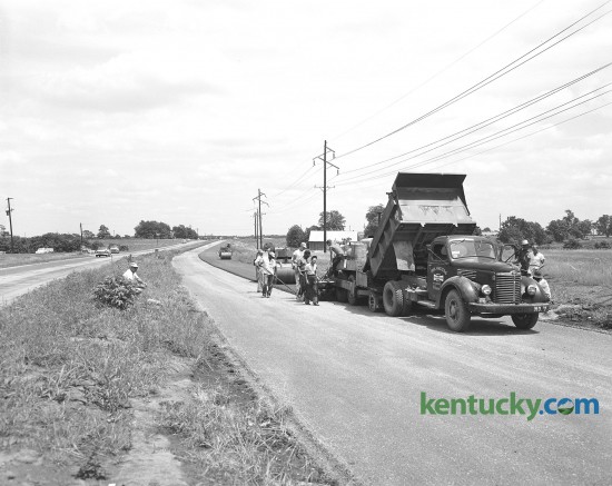 Workers pour the first of three courses of blacktop on a new section of New Circle Road in June of 1958. This section was to be four lanes from west of Newtown Pike to a point near North Limestone Street. 