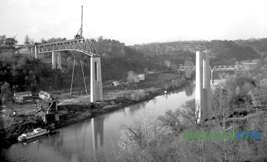 The Clays Ferry bridge under construction over the Kentucky River in November 1944. The task of laying superstructural steel work on the pylons of the new Clays Ferry Bridge was done by the Mt. Vernon Bridge Company of Mt. Vernon, Ohio. The structural work was started from the Fayette county side of the river and rose at a three percent incline to the Madison side, this slight grade can be seen in the photo.  According to the construction company officials, the bridge will be 280 feet in height at river level, the highest structure of its kind east of the Mississippi River, and more than 1,500 feet in length.Published in the Lexington Leader, November 4, 1944.