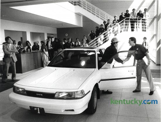The first Toyota Camry produced at the Toyota Motor Manufacturing, Kentucky, Inc. plant in Georgetown. Mike Dodge (right), the plant's general manager, shook hands with Lee Pokriva of the plant's quality control unit after Pokriva drove the car into the lobby of the administration building May 26, 1988. The car was then put on permanent display at the plant. Photo by David Perry, Lexington Herald-Leader staff