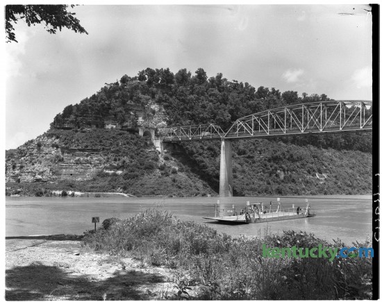 A government operated ferry on the Cumberland River at Burnside, Ky in July of 1950, prior to the formation of Lake Cumberland. Above the ferry is the US 27 bridge and tunnel which were built in 1932. The tunnel can still be seen today just above the water line. A story regarding the formation of the lake and the moving of Burnside to higher ground appeared in the Lexington Leader July 22, 1950. 