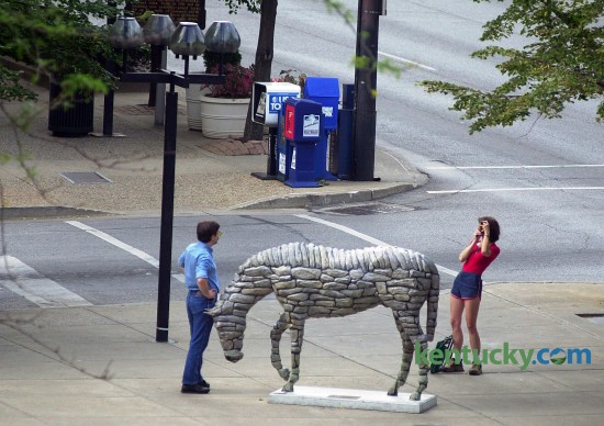 A couple snap photos of one another next to the Horse Mania horse "Stonewall" July 27, 2000 on the corner of Main and Mill Streets in Lexington. The popular public arts project featured 79 horses scattered throughout Lexington. Sponsors paid $1,200 for the horse frame and $2,500 for the artist to design the horse. They were then out for display from July until the the end of November, 2000. In December they were auctioned off, generating $750,000 for Lexington Arts and Cultural Council, and other causes. This horse pictured, "Stonewall", sold for the highest bid at the auction, $53,000. Another Horse Mania was launched in 2010 because of the success in 2000. Photo by Jahi Chikwendiu | staff