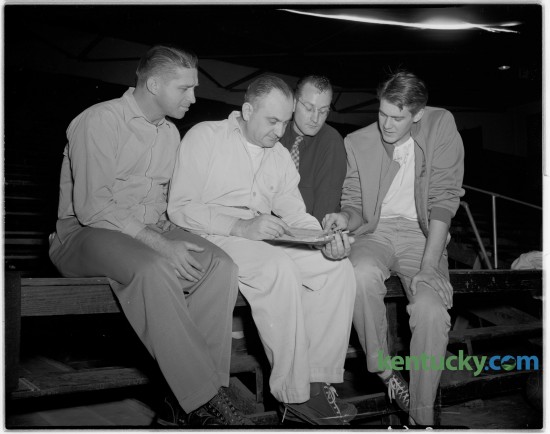 Adolph Rupp looked over a scouting report in December of 1946. With Rupp was assistant coach Harry Lancaster, left, Lester Kling and Ed Lander. Published in the Lexington Leader January 30, 1947. Rupp was born September 2, 1901. 