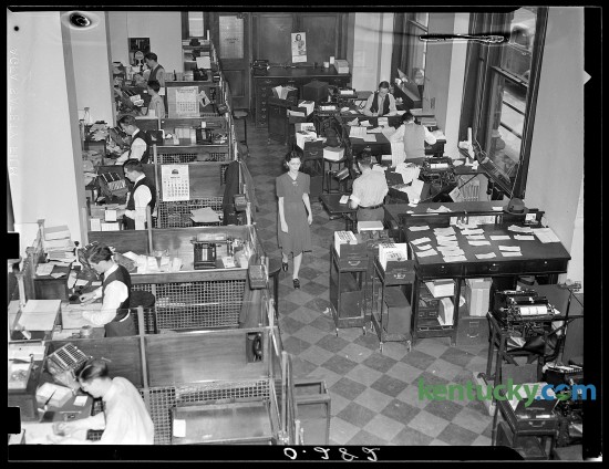 First National Bank and Trust Company founded April 1, 1865 celebrated their 75th anniversary on March 31,1940 with a special ceremony held at the bank.  To promote the anniversary the Leader published this photograph showing an informal view of "behind the scenes" at the First National Bank and Trust Company which showed the interior of the tellers' cages at the left, and a battery of desks, files and computing machines manned by busy clerks and auditors at the right.  Published in the Lexington Leader March 31, 1940. Herald-Leader Archive Photo