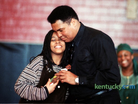 Saida Grundy, 13, got a hug from Muhammad Ali after she presented him with a sculpture by Lexington artist LaVon Williams during Ali's visit to Lexington's Dunbar Community Center on Saturday February 18, 1995. During a daylong visit to the city, Ali, a Louisville native, mingled with the public in the morning, then attended a University of Kentucky basketball game and a reception in his honor afterward. He posed for pictures, signed autographs and playfully shadowboxed with kids. The visit, part of African-American History Month, also was intended to promote the play "Ali" the next weekend at the Lexington Opera House. Ali, then 53, did not speak much during his 2 1/2-hour morning visit with about 300 at Dunbar Community Center. He suffers from Parkinson's disease, and talking is difficult for him. But his actions said plenty to the crowd. He cuddled and kissed babies, embraced his fans and signed everything from scraps of paper to boxing gloves to a Muhammad Ali pinball machine. By the time he left, he had a smear of pink lipstick on his left cheek and dozens of small boys clutching at his coattails. Photo by David Perry | Staff