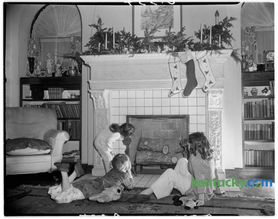 Dottie Bruce Davis, standing, daughter of Mr. and Mrs. Finley Davis, 216 South Hanover Avenue, and seated, Jock and Betty Sheehan, grandchildren of Mr. and Mrs. L.C. Foster, 204 South Hanover Avenue posed for a photo in front of the Davis fireplace prior to Christmas in 1945. Published in the Herald-Leader, December 23, 1945.