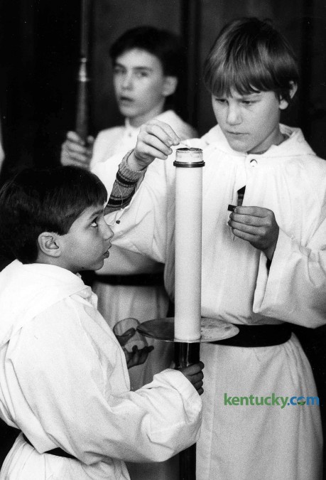 Altar servers Paul Thorpe, left, and Brad Ohnheiser light the processional candle just before mass  Feb. 22, 1986 at St. Paul Catholic Church in Lexington. To the rear is Tony Good. Photo by Gary Landers | staff