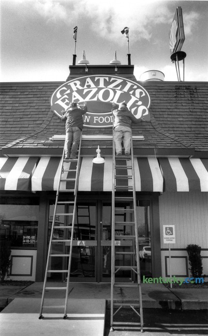 Martin Sherrod, left and Clint Sherrod of the Sherrod Sign Company change the sign on Gratzi's, on North Broadway in Lexington, to it's new name, Fazoli's, February 10, 1989. The companies first Italian fast-food first restaurant on North Broadway near the Interstate 75-64 interchange, had been operated by Jerrico under the Gratzi's name since September 1988. But surveys of potential customers showed that they kept confusing "Gratzi's" - taken from the Italian word for "thank you" - with the name of Canadian-born hockey player Wayne Gretzky, said Robert L. Sirkis, Jerrico's executive vice president. After hiring three naming firms and looking at tens of thousands of names, Jerrico decided to replace Gratzi's with Fazoli's. Which means . . . nothing. "It is completely made up," Sirkis said. The company, still based in Lexington, currently operates 217 restaurants in 26 states. Photo by Clay Owen | staff