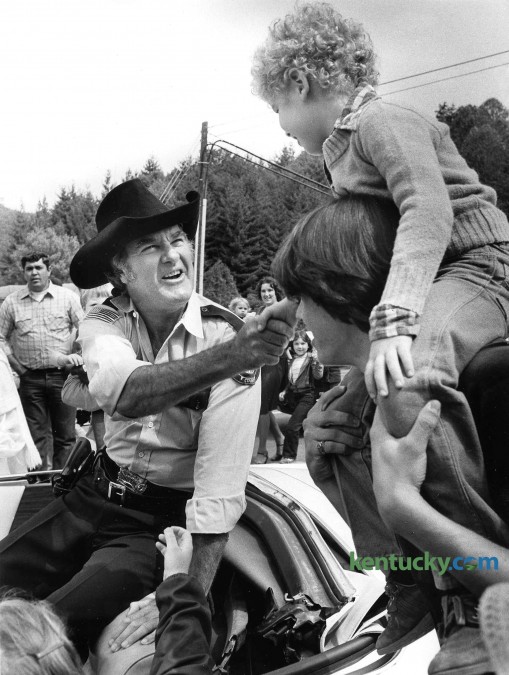 Actor James Best, better known for playing the giggling and inept Sheriff Rosco P. Coltrane on "The Dukes of Hazzard," shakes hands Sept. 19, 1981 with Travis Goff, 6, of Jackson during Perry County's Black Gold Festival in Hazard. Best, along with three other of the show's TV characters - Boss Hogg (Sorrell Booke), Daisy Duke (Catherine Back) abd Cletus (Rick Hurst) - served as grand marshalls in a parade and helped dedicate Hazard's new $1 million city hall. Organizers estimated the crowd to be "30,000 to 40,000" people. While in Hazard, Best met up with a brother he had not seen in 50 years. Best was born in the Western Kentucky coal-mining community of Powderly, near Central City in Muhlenberg County. One of nine children, he was adopted from an Indiana orphanage at the age of 4 after his mother died. Through the years he had lost contact with many of his siblings. Best died April 6, 2015 from complications of pneumonia. photo by David Perry | staff