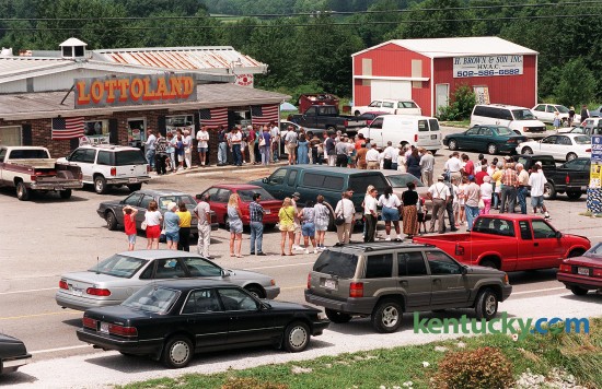 Patrons of Lottoland stood in line July 28, 1998 in Franklin, Ky. near the Tennessee border, to buy tickets for an estimated $250 million Powerball jackpot. Store owner Don Spears said he sold $50,000 to $60,000 worth of Powerball tickets daily during this latest frenzy. From the moment the doors opened at 8 a.m. to closing time at 10 p.m., players lingered in the Lottoland parking lot, awaiting their chance to trod the worn red carpet from the front door to the lottery registers in back. Spears keept the doors locked to satisfy the fire marshal, opening it for only two dozen people at a time. When they reach the L-shaped counter with the registers, they pull out rolls of ten-, twenty- and hundred-dollar bills. "One guy spent $8,000," Spears said. "He had cash." Kentucky Lottery spokesman Rick Redman said Lottoland, which is a quarter mile from an Interstate 65 exit just north of the Tennessee state line, is one of the biggest lottery sellers in the state. It is still open today. A group of machinists who called themselves "The Lucky 13" stepped forward to claim the $295.7 million Powerball jackpot - the biggest prize to that date. Photo by David Stephenson | staff