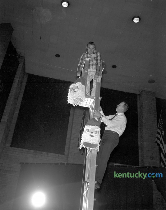 Jack Gallagher, left, and Jim Flynn, members of the Lexington Junior Chamber of Commerce are shown hanging some of the decorations for the annual Christmas party for all Central Kentucky children, set for Sunday afternoon December 10, 1961. Herald-Leader Archive Photo