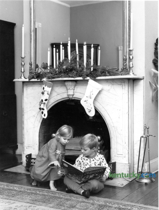 Margaret Gay Haggin, 2, and Louis Lee Haggin IV, 5, read The Night Before Christmas in front of the fireplace at the Hunt-Morgan House in December 1964. Margaret and Louis are the children of Mr. and Mrs. Louis Lee Haggin III of Lexington. Published in the Lexington Herald December 20, 1964. Photo by John C. Wyatt | Staff