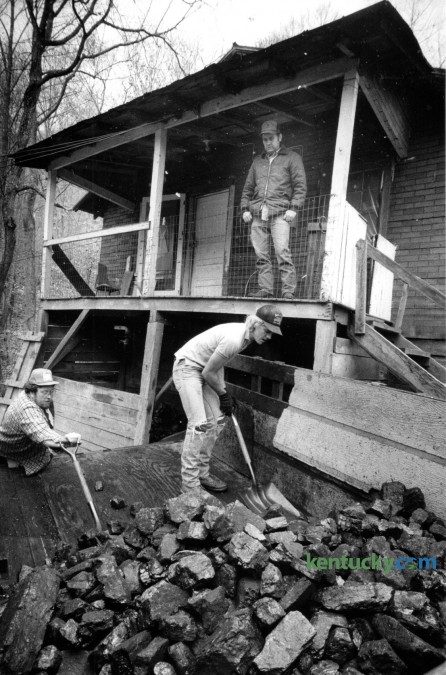Oliver Meade watched from his porch as Jellen Meade, left and Harold Meade unloaded about 3 tons of coal at his home in Deane, Ky. on December 4, 1990. The photo ran with a story about a federally funded program that provided free coal for needy families in Leslie, Perry, Letcher and Knott counties. Photo by Charles Bertram | Staff
