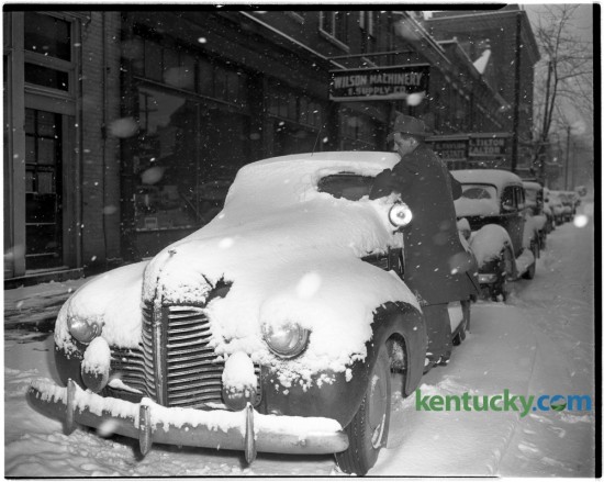 An unidentified man cleaned the snow off his car in front of Wilson Machinery and Supply Company, 139 North Mill Street, after Lexington received four and a half inches on December 5, 1945. Published in the Lexington Leader December 6, 1945. Herald-Leader Archive Photo
