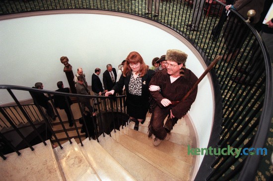 House Democratic Leader Greg Stumbo of Prestonsburg climbed the steps in the Old Capitol in Frankfort with Charlotte Ellis, his chief of staff Jan. 6, 1998 during the opening day of the General Assembly. As the 20th century drew to a close, lawmakers decided to meet in the same building where legislators gathered at the start of the century. Wearing buckskin britches and coonskin caps, Stumbo and about a dozen fellow Eastern Kentucky Democrats referred to themselves as "The Mountain Caucus". The group wore the pioneer garb, borrowed from a Central Kentucky theater troupe, to symbolize a feeling that Eastern Kentucky has been left behind by the rest of the state and the lawmakers' determination to get more money this session for their region's needs. Photo by Charles Bertram | staff dressed as Daniel Boone carrying a Kentucky long rifle  and accompanied by his chief of staff  Charlotte Ellis, , climbs the stairs in the Old State Capitol in Frankfort Ky on Tuesday January 6, 1998. The General Assembly meet there today, for their first day of the 1998 session.