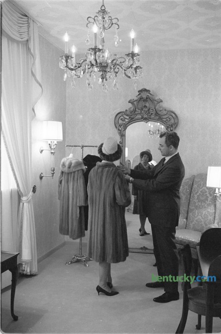 The president of Embry's, William R. Embry Jr. helped a customer decide on a  fur coat in the second floor Crystal Room, which provided seclusion for those wishing to view furs. The photo ran with a story about the grand re-opening of their remoded downtown store, located at 141 East Main Street, in December 1966. Embry's, known as Kentucky's premier fur and fashion boutique first opened in 1904 specializing in hats and the "finest ladies fashions". The business continues today and is now located in the Lansdowne Shoppes. Published in the Lexington Herald-Leader December 4, 1966.