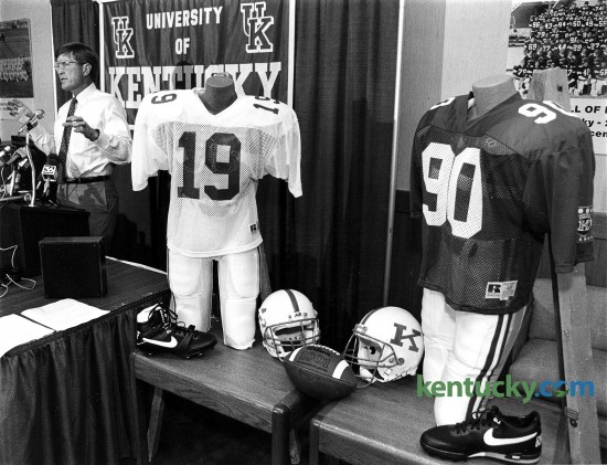 First-year University of Kentucky football coach Bill Curry unveiled new uniforms a week before his freshmen reported for pre-season practice, July 27, 1990. A pair of mannequins were on hand, sporting the Wildcats' new less-means- more uniforms, complete with the player-popular black footwear. Curry said there was no major significance in the fact that the new coach decided to place his first Kentucky team into a set of subtly different duds. And no, said Curry, he did not try to pattern UK's new attire after any particular team, save maybe his old Baltimore Colts. "I think the uniforms look good, and that's all we need," said the coach. Simplicity being the Curry look for the '90s. Basics remain - white helmets with a blue "K" on the side, blue jerseys, white pants. Gone are the two blue stripes down the center of the helmet, replaced by a single stripe. Gone are the blue pants. The Cats will wear white trousers home and away. Gone are stripes on jersey sleeves, replaced by a single patch commemorating the school's centennial football season. Gone, too, are white shoes, replaced by your basic black models. Because, said Curry, "The players like the black shoes." Photo by Charles Bertram | staff