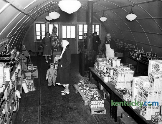 Interior view of the community grocery store in Cooperstown on the University of Kentucky campus, Jan. 1948. Cooperstown was a village of apartments, built in 1946 to house veterans who enrolled at UK. C. A. Shields, manager, is pictured in a white apron behind the counter. The grocery, which opened on Jan. 16, 1948 to service the more than 500 students veterans and faculity familes living in the housing complex, was a converted Army quonset hut. Published in the Lexington Leader January 23, 1948. Herald-Leader Archive Photo