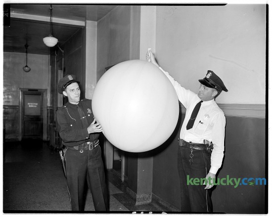 Lexington patrolmen Robert Duncan, left, and Stanley Hadley examine a large rubber balloon which landed on North Mill Street near Second Street on the evening of Aug. 29, 1945. Residents in the area were frightened by the possibility it may have been a Japanese balloon bomb. A small crowd of people kept a safe distance while officers examined the balloon. The police took the balloon to their headquarters where they deflated it and discovered it contained natural gas. No identifying marks were visible on the balloon and officers were puzzled as to its possible origin. Published in the Lexington Herald on Aug. 30, 1945. Herald-Leader Archive Photo ****8/30/1945***on Page O.332