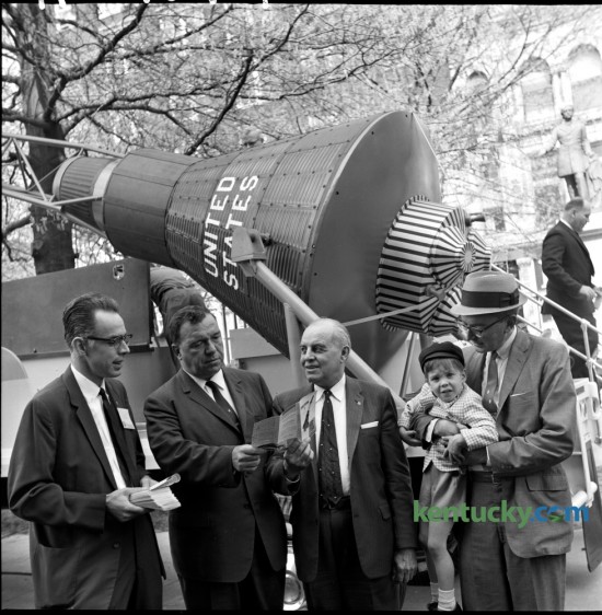 As part of the Freedom Bond Drive, a duplicate of Col. John Glenn's Mercury 7 space capsule was displayed in Cheapside Park on Friday April 27, 1962. Posing in front of the capsule was Bill Staton of the Lexington Jaycees, Robert Stilz, county savings bond sales chairman, County Judge Bart Peak and Lexington Mayor Richard Colbert, holding his son Richard. The primary purpose of the space capsule's visit to Lexington was to remind local residents of the Freedom Bond Drive and to urge them to invest in the bonds as well as giving them some idea how some of their taxes for defense are invested.  Published in the Lexington Leader April 28, 1962. Herald-Leader Archive Photo