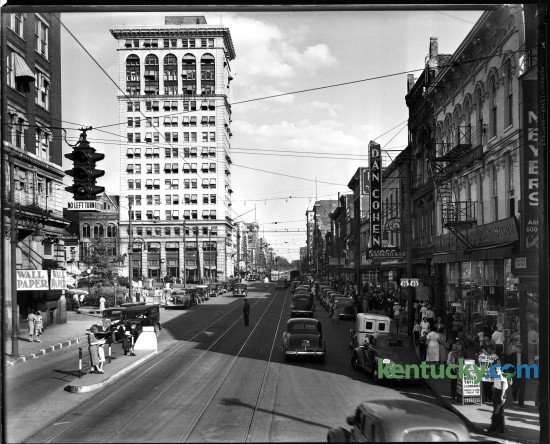 Main Street, downtown Lexington, circa summer 1938. Rails run down the street, but around this time streetcar service was discontinued in Lexington. Like most American cities, as roads were improved and more people bought automobiles, trolley tracks were pulled up or paved over. Motor buses took over the steadily declining demand for public transportation. In the lower left corner of the picture you can see two women and a child waiting for the bus that coming towards them. Along the left side is what is now Cheepside Park. Further down is Lexington's first skyscraper, the First National Building. Built in 1913, it is now a 21c Museum Hotel. The buildings on the right include a Woolworth five-and-dime store and clothing store B.B. Smith & Co., whose sign said it was "Correct Appareral for Women & Misses". This is now the site of the Lexington Financial Center, or more commonly known as the "Big Blue Building". Herald-Leader archive photo