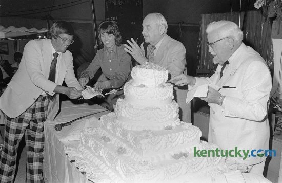 Former University of Kentucky basketball coach Adolph Rupp, center, and Kentucky Fried Chicken founder Col. Harland Sanders, right, cut a cake in observance of Lexington radio station WJMM's first anniversary, July 25, 1974. Also participating in ceremonies in the Gospel Music Tent at Blue Grass Fair were the Rev. Jack Mortenson, station owner, and Ms. Kay Chaney, assistant to the station manager. The radio station, a Christian teaching-talk station, has now served Lexington and surrounding communities for over 40 years. At the time of this photo, Rupp was 72 and had been retired for two years. Sanders was 83 at this time, 10 years since he sold the company to a group of investors led by John Y. Brown, Jr. and Jack C. Massey for $2 million. Published July 26, 1974 in the Lexington Leader. Herald-Leader Archive Photo