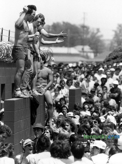 Despite the threat of barbed wire fence, infield patrons climbed up the outside of a restroom entrance May 7, 1983 at Churchill Downs. Not more than 100 yards away were several dense clumps of bushes that served as alternate restroom space as the afternoon wore on. Photo by CHarles Bertram | staff