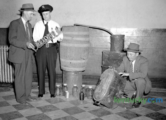 Jessamine County Sheriff Harvey Partin, left, and Nicholasville Police Chief Carl Bruner examine parts of confiscated 50-gallon moonshine still, May 14, 1947. The equipment consisted of a sour mash barrel, complete worm, condensing barrel, boiler, 12 half-gallon jars and several half-pint bottles. The officers said it had recently be used. Three days later, a jury of 10 men and two women convicted two men with possessing the still. County Judge T.R. Guyn gave them each $250 fines and three months in jail. Published in the Lexington Leader May 15, 1947. Herald-Leader Archive Photo