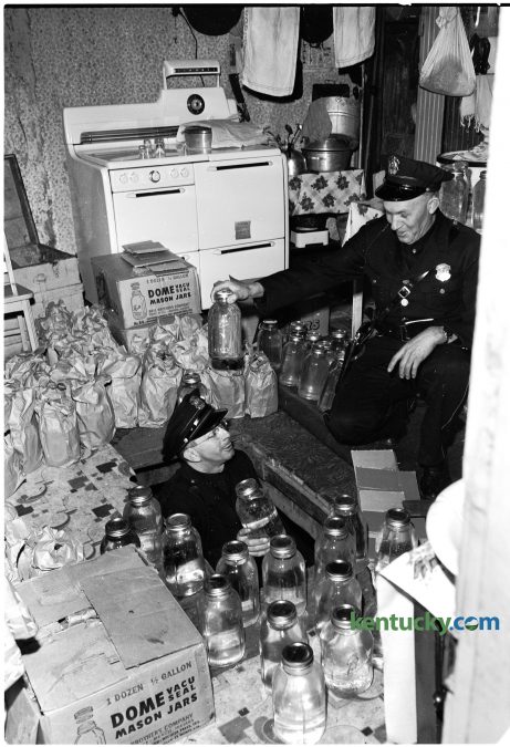 Lexington police officer Harrison Sallee passes confiscated moonshine jars to officer Jesse Wilburn Jan. 11, 1951. The house at 536 Brown Court was raided in what police described as the biggest moonshine raid in local history. 188 gallons of the liquor were well hidden under the kitchen floor, which was accesiable through a trap door. All of the moonshine was stored in fruit jars, officers said. Four men were arrested during the raid. Herald-Leader archive photo