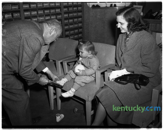 Toddler Kathy Lewis being fitted by S.B. Foley with pair of shoes at Baynham Shoe Company, Feb. 4, 1949. The popular shoe store founded by three brothers at 135 East Main Street, operated for more then 50 years before closing in the 1970s. Their motto was "shoes of distinction". Around the time of this photo, they were advertising white buck shoes for men for $4.95 a pair. The site of where the store was is where Phoenix Park is.