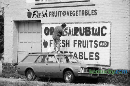 Dennis Myers, owner of Equus Art & Sign Painting, painted  over the word 'wholesale' to change it to Open to the Public, on the side of Baltrip's Fruits and Vegetables, 317 Bolivar Street on September 12, 1991. Photo by Charles Bertram | Staff
