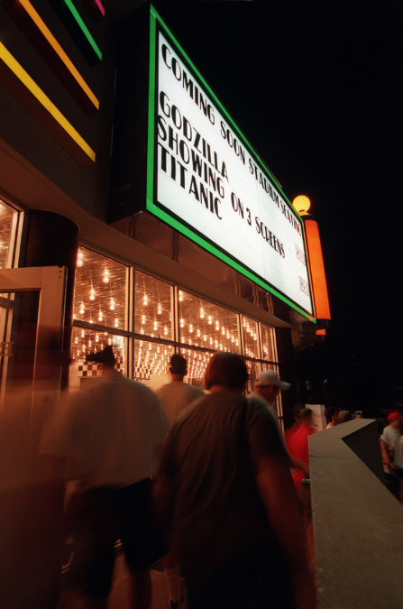 People leaving the Woodhill Movie Theater after seeing the 7:00 p.m. show of the movie Godzilla, May 19, 1998. As the marque says, the film was shown on three screens. It was the ninth top grossing film released in the nation that year. "Titanic", the other movie on the marque, opened six months earlier in December 1997 and was so popular that it was still being shown in theaters. Photo by Joseph Rey Au