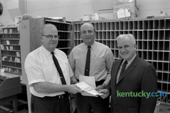 Postal employees Scott Johnson, left, clerk, and William B. Keightley,  center, carrier, received Superior Accomplishment Awards from Tom Bradley, right, superintendent of the Gardenside branch post office in December 1969. The award was for a contribution or performance that was over and above normal work requirements for an extended period of time. Keightley, the long time Kentucky basketball equipment manager who died March 31, 2008, would have turned 90 years old today. Herald-Leader Archive Photo
