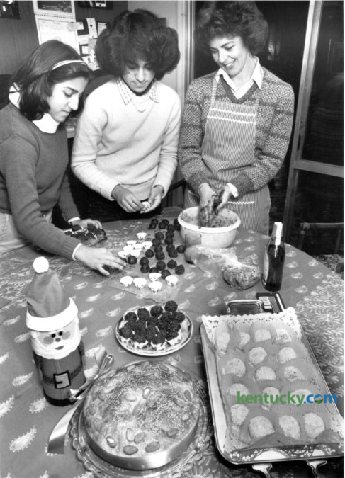 Helen Digenis, right, with her daughters Melina, 13, left and Emily, 15, prepared chocolate truffles and other holiday sweets in their kitchen on December 14, 1981. In the foreground are vassilopita, left, a Greek New Year's cake and kourambiethes, a Greek butter cookie, right. Photo by David Perry | Staff