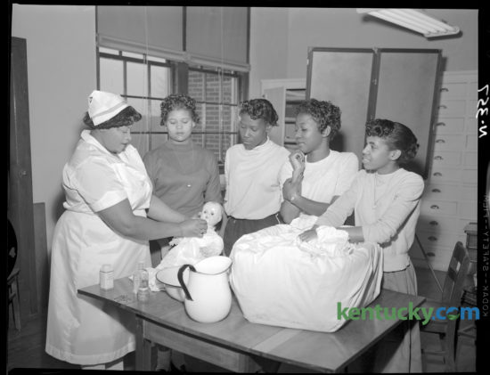 Baby-care techniques were demonstrated by Mrs. Fannie Foster, left, a licensed practical nurse and Red Cross nurse instructor,  to members of a Red Cross home-care of the sick class at Douglass High School in February 1957. Watching are, from left, Loretta Beatty, Charles Anna Brown, Delores Edwards and Carolyn Jackson. They were among 15 junior and senior home economics students enrolled in the class, which met for a total of 15 hours. Herald-Leader Archive Photo